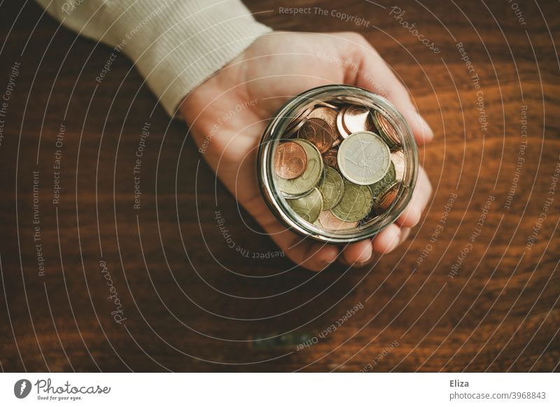 One hand holds a jar full of coins. Saving. Coin Save Money Hand Bird's-eye view Glass Money box Euro Loose change Coins stop small livestock small change Wood