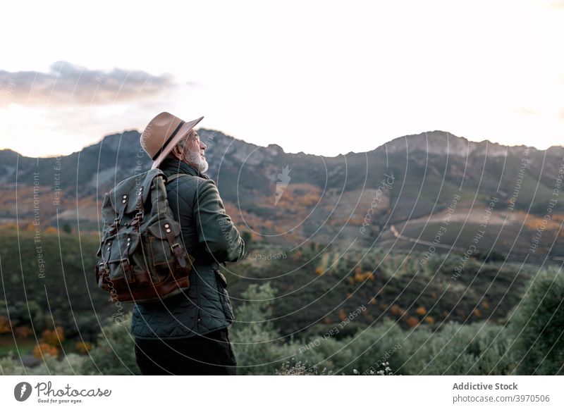 Senior wanderer standing on hill in mountains senior man scenic highland cold season male caceres extremadura spain admire scenery landscape picturesque