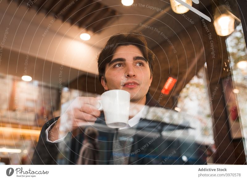 Young man drinking coffee in cafe enjoy window young cup rest break positive male cozy lifestyle beverage hot drink smile free time chill coffee shop content
