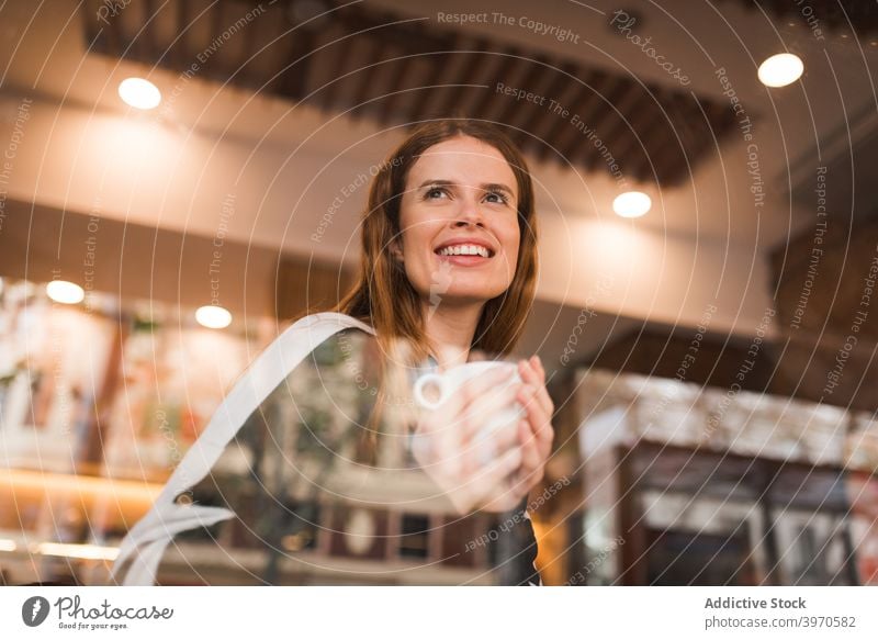 Happy woman with cup of coffee resting in cafe caffeine drink enjoy window young cheerful chill break positive female cozy lifestyle beverage hot drink smile