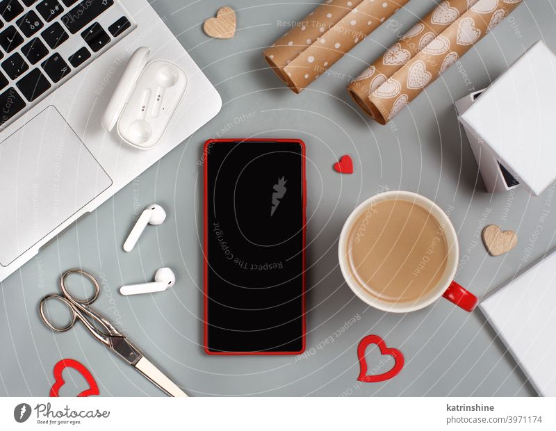 Red Mobile phone and cup of coffee near laptop. Valentines Day concept Wrapping valentine day gift mockup smart working home smartphone Hearts earphones