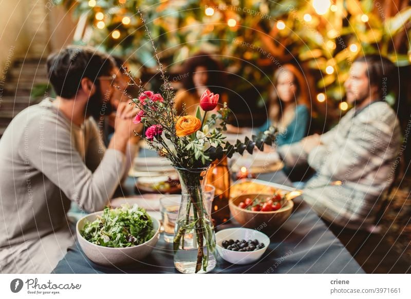 friends at dinner table with flowers and food Adult Candid Outdoor Young Adult alcohol backyard celebrating chatting dinner party diversity drinking eating