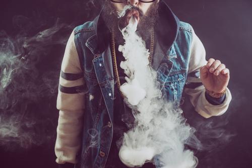 Young man with beard throwing a cloud of steam. Black background. Vaping an electronic cigarette vape vaping smoke adult cool lifestyle person smoker habit