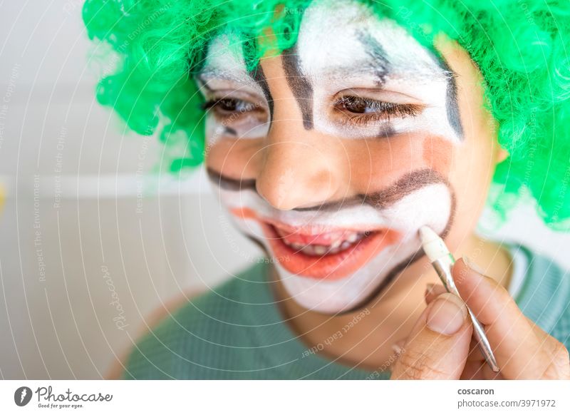 Mother painting her son's face like a clown art boy brush carnival caucasian celebration child childhood circus close up color colorful costume cute face paint