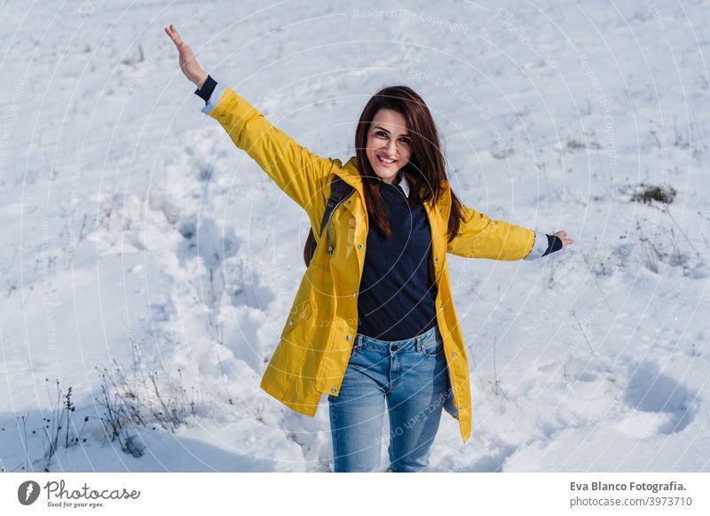 happy woman hiking outdoors in snowy mountain. Nature and lifestyle yellow coat caucasian travel wanderlust backpack time out wellness liberty arm nature sun