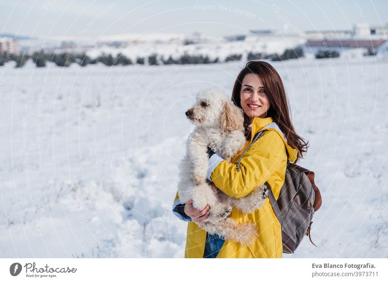 backpacker woman hiking outdoors with cute poodle dog. Snowy mountain in winter season. nature, pets and lifestyle snow yellow coat happy smiling travel daytime