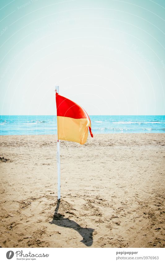 lonely flag on empty beach Flag Red Wind Flagpole Blue Deserted Yellow Judder Blow Sky Exterior shot Clouds Beach Walk on the beach Sand Ocean Water vacation