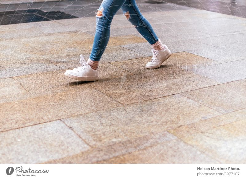Closeup shot of a female walking on wet asphalt in the street. city buy lifestyle clothes fashion recreation squander business winter brand shoes running urban