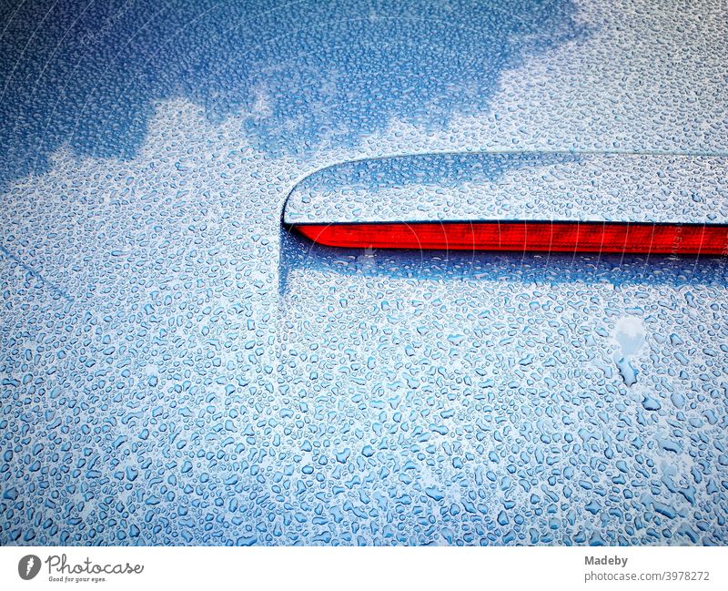 Water drops on the blue trunk of a convertible with red middle brake light on a rainy day in summer in Germany Rain Rainy weather Drops of water showers