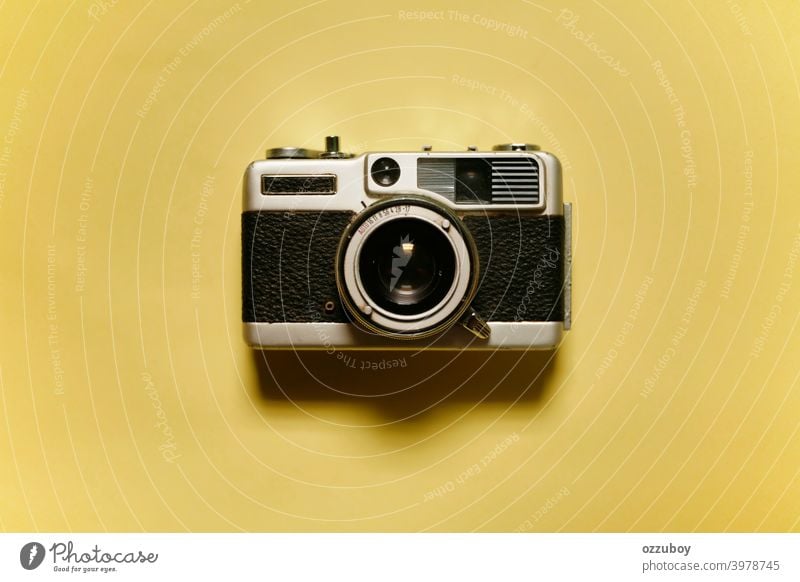 front view of vintage analogue photo camera isolated on yellow background old equipment film lens antique classic photography retro black metal technology white