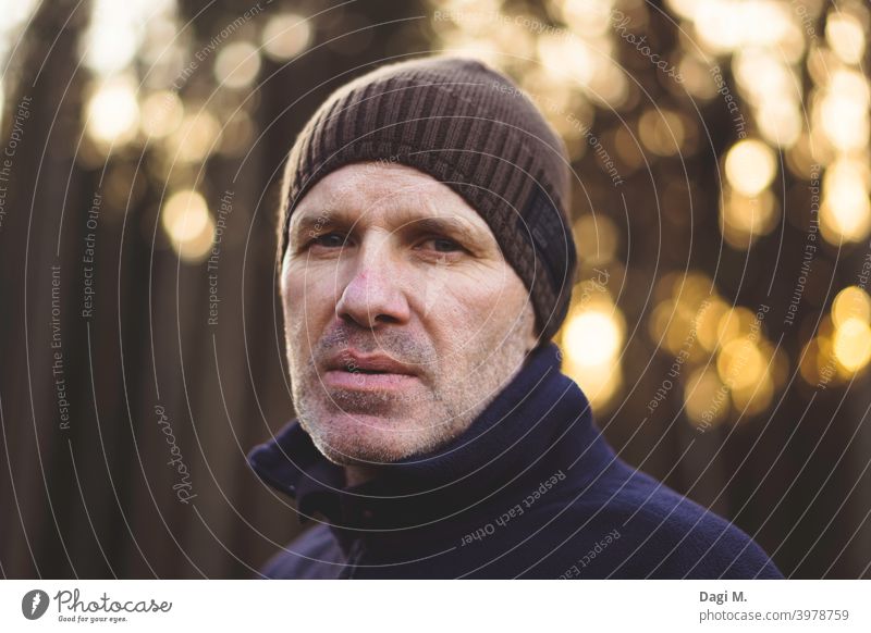 Man with cap stands in front of forest edge, bokeh in background, Earnest monitoring temporising Edge of the forest clearer To go for a walk outdoor