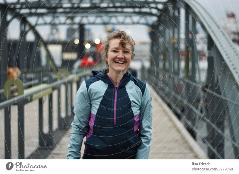 SPORTY - LAUGH - HARBOUR Woman 30 years old Blonde Curl Laughter Athletic Adults Happiness Bridge Bridge railing Harbour Hamburg Track-suit top