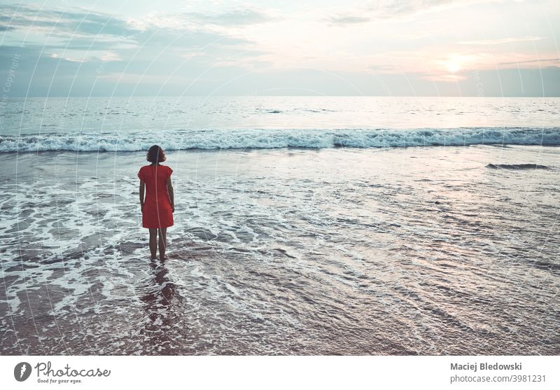 Woman stands in the ocean at sunset. girl beach water woman sea loneliness depression summer nostalgia faded sky horizon wave female sunrise young vacation