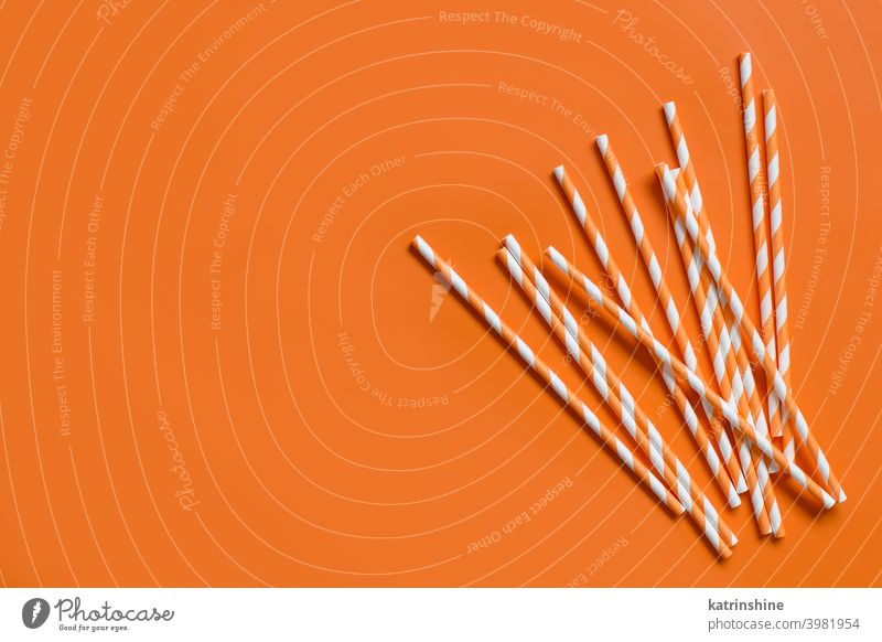Striped paper drinking straws on orange background top view biodegradable copy space Eco friendly Cocktail monochrome Colorful Recycling concept suck minimal