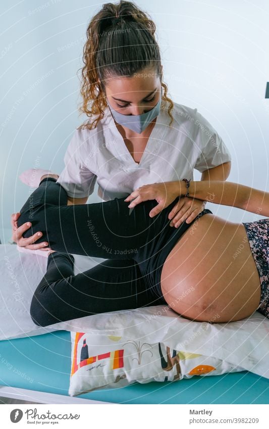 Female therapist stretching leg of pregnant during physiotherapy session in contemporary clinic. pregnancy prenatal physiotherapist rehabilitation massage woman