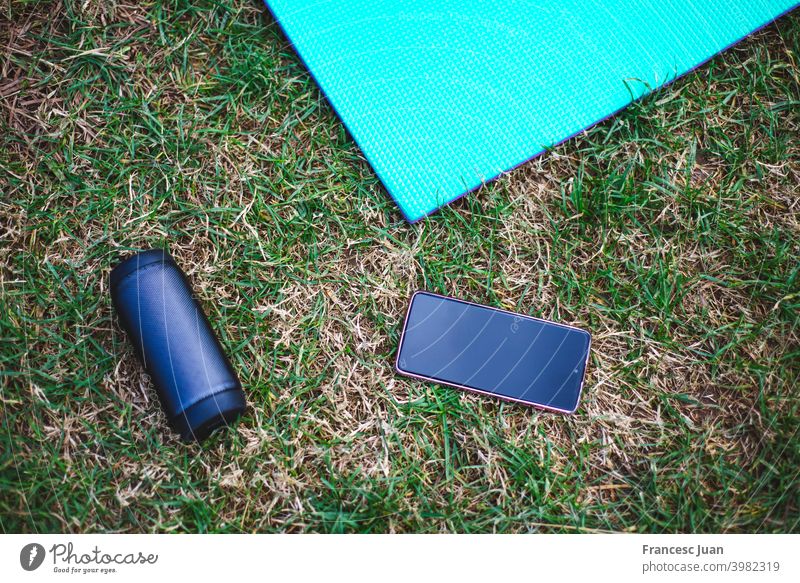 High angle shot of a yoga mat, a smartphone and a loudspeaker high vertical black red wood wooden table music mobile display communication electronic media
