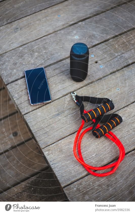 High angle shot of an exercise rope, a smartphone and a loudspeaker high vertical black red wood wooden table music mobile display communication electronic