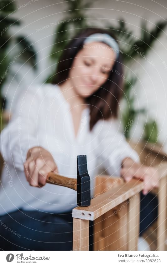 close up of young woman assembling furniture at home working with hammer. DIY concept do it yourself house caucasian indoor renovation young adult craft