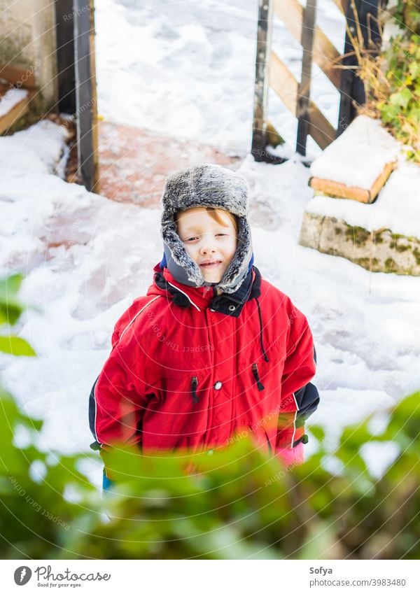 Little blonde boy in winter outerwear outdoors child snowsuit happy little look face eyes white caucasian kid cold hat cap cute fun season playing clothing