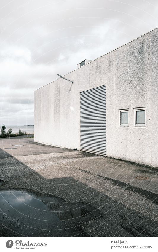 White facade of a warehouse with closed roller shutter door Industrial plant Warehouse Building Facade Wall (building) Gray Rolling door Closed Perspective