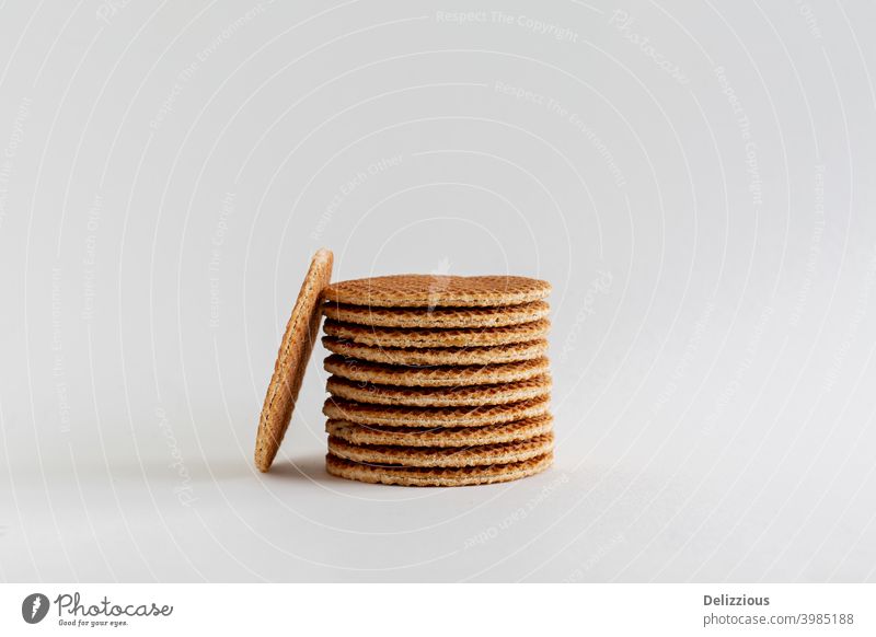 A stack of Dutch stroopwafels (syrup or caramel waffles) with one cookie in the side on a white background with copy space, close up bake bakery biscuit