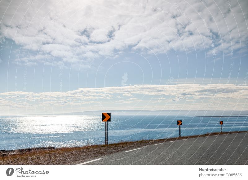 Coastal road on Varanger in the Finnmark of Norway Street Ocean coast Curve Driving Vantage point sign Sign sparkle Sun Summer travel vacation reflection