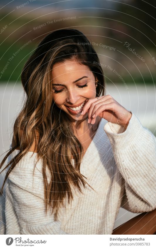 Happy young female in stylish sweater smile rest yard happy style touch face eyes closed tender appearance long hair knitted soft delight casual cheerful joy