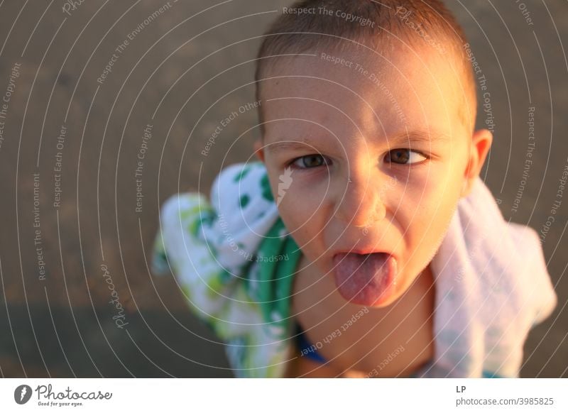 child sticking his tongue out Looking into the camera Portrait photograph Upper body Sunset Sunrise Sunbeam Sunlight Light Structures and shapes Exterior shot