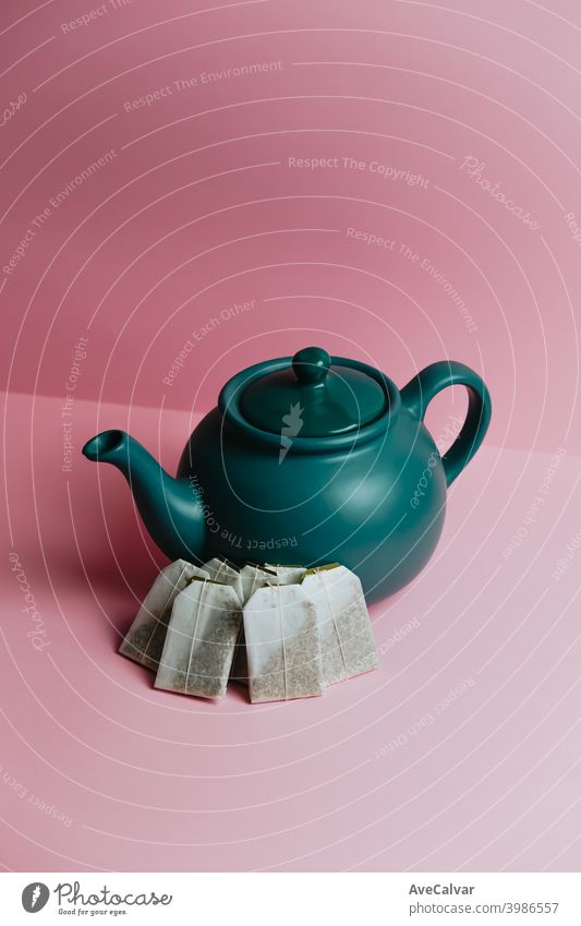 A minimalistic blue teapot and fast tea envelopes over a pastel pink background conceptual copy-space marketing sparse graphic luxury idea temptation