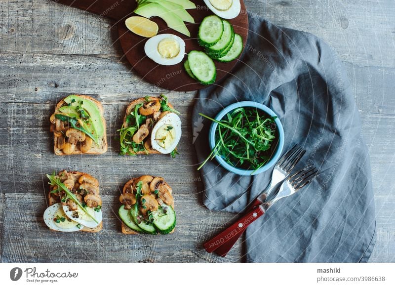 various morning vegetarian toast set with mushrooms, avocado, arugula, cucumber, micro green and eggs. Healthy food on rustic wooden background bread vegetable