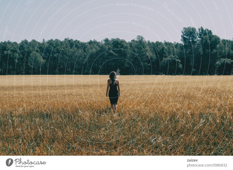 girl walking through a beautiful yellow field horizontal peace tranquility produce growth golden land light outside color image idyllic panoramic path scenics