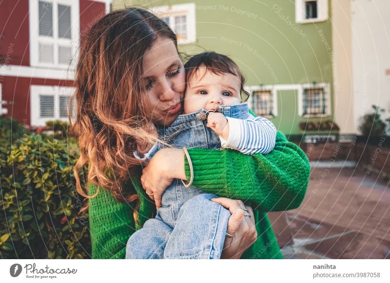 Lovely young baby in her mother arms family motherhood mom green urban long hair time trave holidays jeans casual wear young mom people real love hug