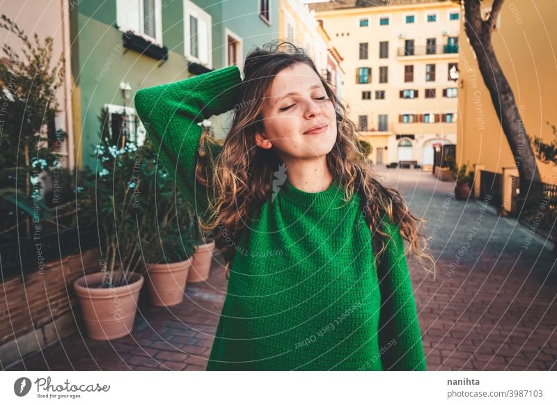 Young woman wearing green oversize sweater enjoying a windy day in a colorful city travel portrait lifestyle model europe european blonde female outdoors free