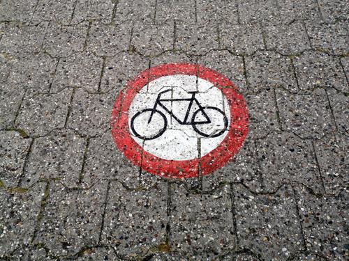 A round traffic sign painted on the composite pavement prohibits the passage of bicycles on the dyke at the harbour of Neuharlingersiel near Esens in East Frisia in the district of Wittmund in Lower Saxony