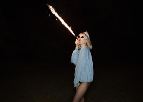It's Friday night and I feel all right. The party is here on the West side. Blonde girl is blowing fire and having some good times. fireworks pretty legs