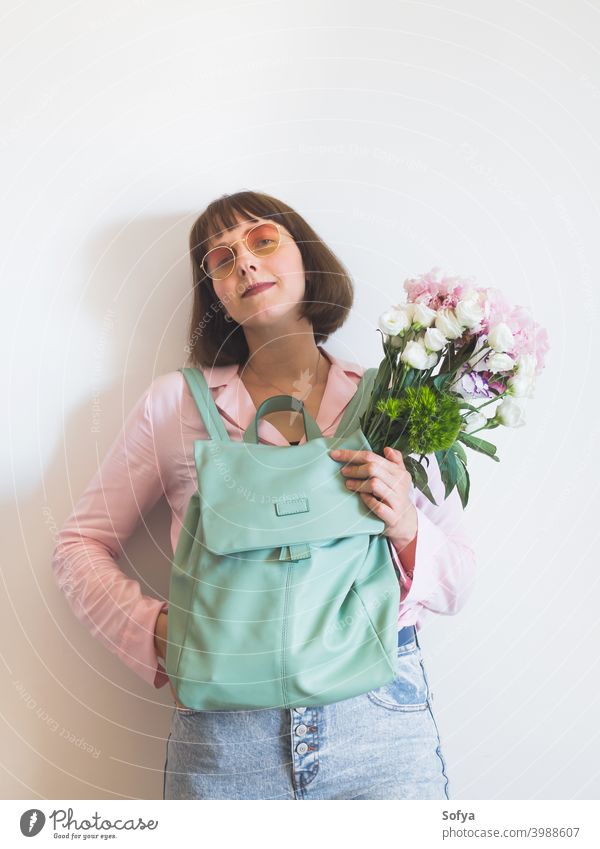 Young woman in pink with backpack and peony bouquet mother spring day authentic mothers day flowers face lifestyle womens day smile pastel expression concept