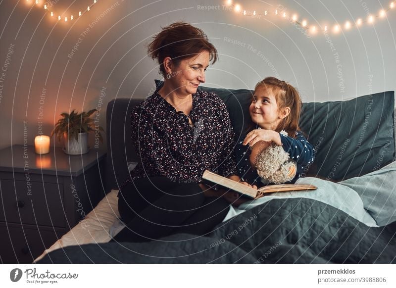 Mother reading book her daughter in bed before going to sleep. Bedtime stories for child night mother bedtime family home literature woman bedroom fairy parent
