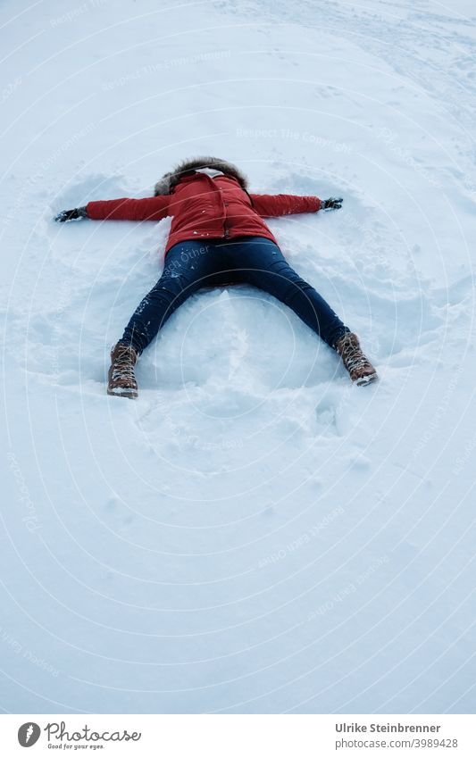 Woman in red anorak makes a snow angel Snow Winter fun snow angels Anorak Virgin snow winter fun Angel angel wings Imprint Meadow Snow layer White Cold