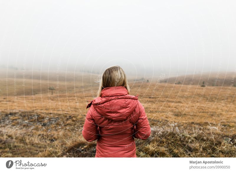 Young woman exploring nature on a foggy winter morning adventure autumn cloud cold countryside discovery exploration explore explorer female field freedom grass