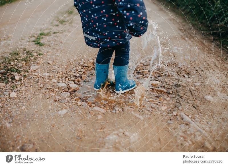 Child with red rubber boots playing on a puddle Puddle Rubber boots Winter Rain Water Wet Human being Exterior shot Colour photo Playing Joy Boots Dirty Mud