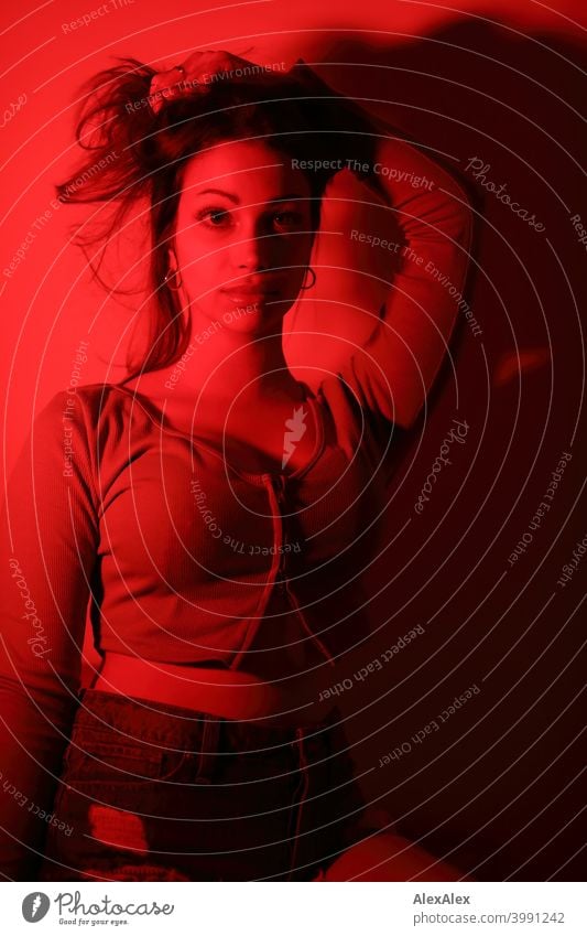 Portrait of a young woman in a room with red light - the whole picture is red Young woman pretty Brunette Long-haired Slim Feminine teenager 18-25 years