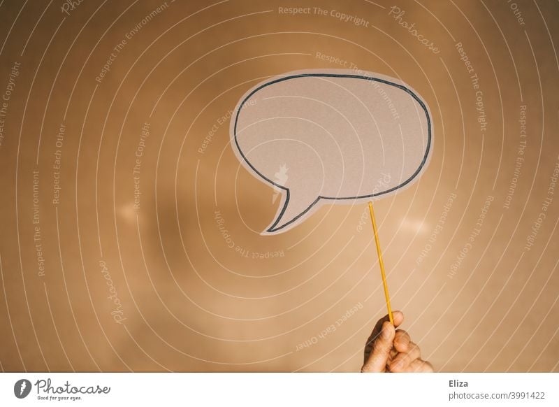 Hand holding an empty speech bubble in front of brown background Speech bubble Brown Empty communication Copy Space copyspace Communicate Say Opinion