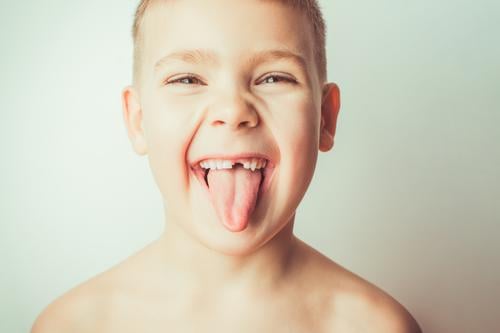 Funny boy with no tooth shows tongue little child care male person background mouth face portrait childhood funny teeth happiness white beautiful smile without