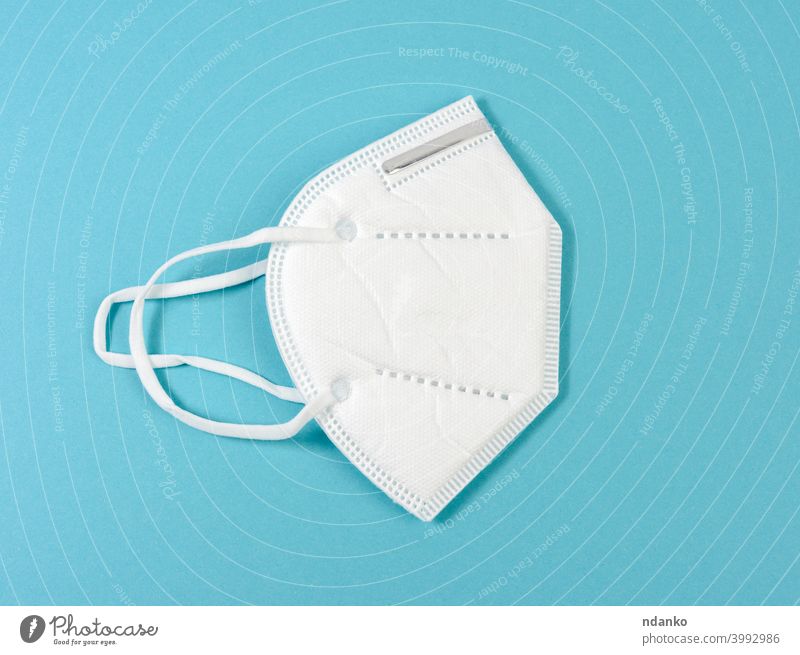 white disposable medical mask on a blue background, personal protective equipment for the respiratory tract from viral infections medicine pandemic pneumonia
