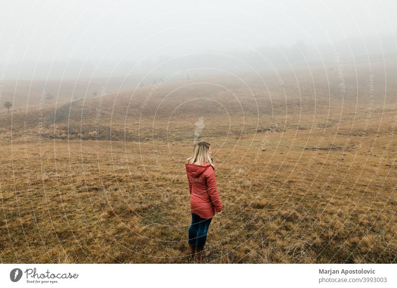 Young woman exploring nature on a foggy winter morning adventure autumn cloud cold countryside discovery exploration explore explorer female field freedom grass