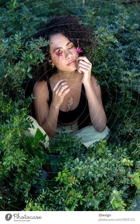 Outdoor fashion photo of beautiful young woman surrounded by plants flower beauty summer curly female girl portrait face hair model cute lifestyle outdoor enjoy
