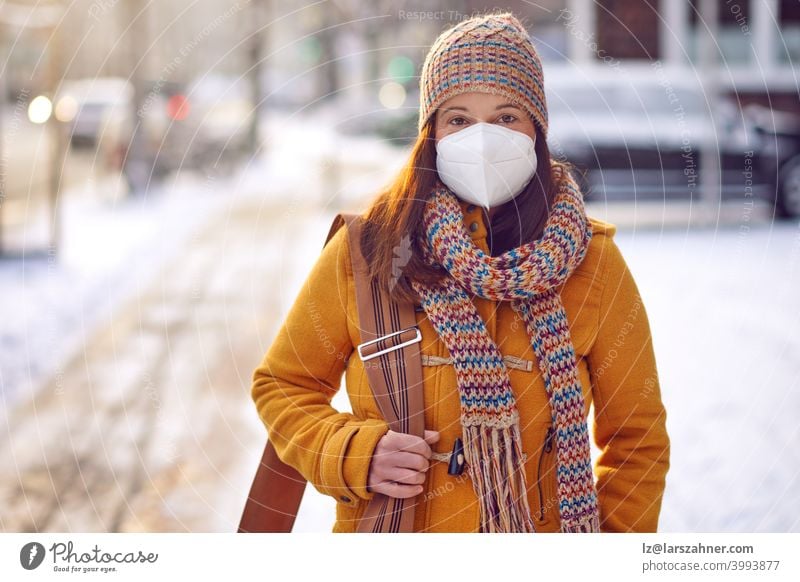 Middle-aged brunette woman in winter clothes wearing face mask outdoors due to Corona virus outdoors while on her way to work middle-aged ffp2 protection safety