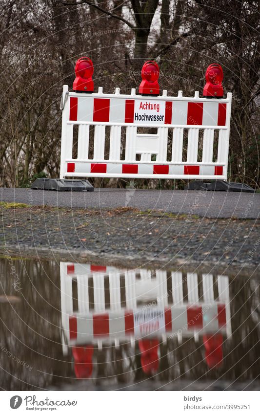 Official closing of a way because of high water. Beacon with warning sign reflected in the water Flood cordon inundation off peril reflection Warning sign