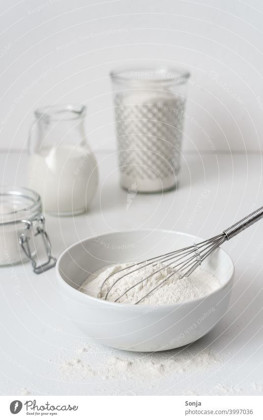Flour in a bowl and ingredients on a white table Milk Sugar Breakfast bake a cake Table White Storage tank Glass Preparation dough Kitchen Baking Food