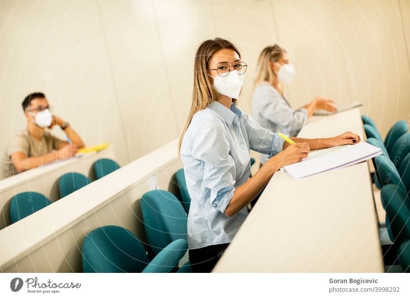 Female student wearing face protective medical mask for virus protection at lecture hall college education woman young university disease coronavirus pandemic